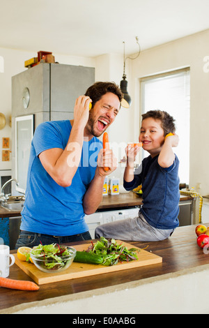 Vater und seinem kleinen Sohn in Karotte Mikrofone zu singen Stockfoto