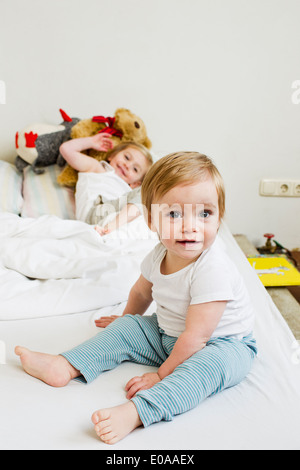 Porträt von Mädchen auf dem Bett mit ihrer Schwester Stockfoto