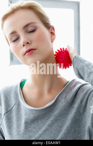 Junge Frau mit Massage-Ball am Hals Stockfoto