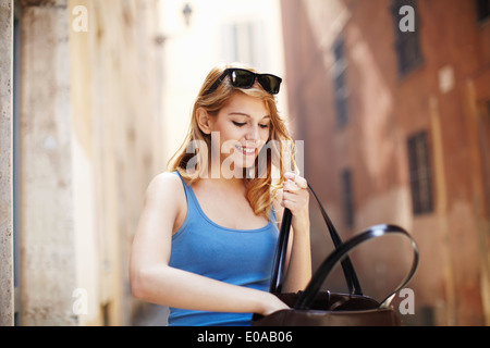 Junge Frau Suche in Umhängetasche, Rom, Italien Stockfoto