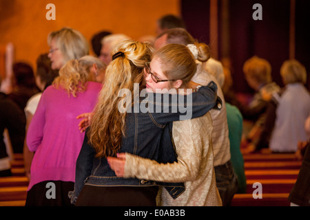 Eine Mutter und ihre Teenager-Tochter hug zum Abschluss der Messe in Laguna Niguel, CA, katholische Kirche. Stockfoto