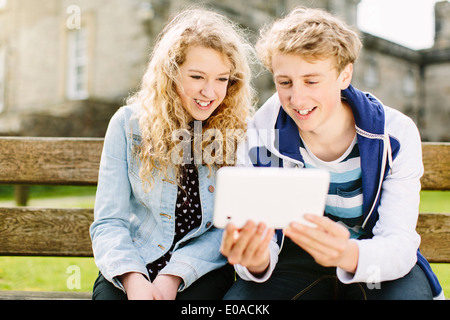 Teenager Bruder und Schwester Blick auf digital-Tablette auf Bank Stockfoto