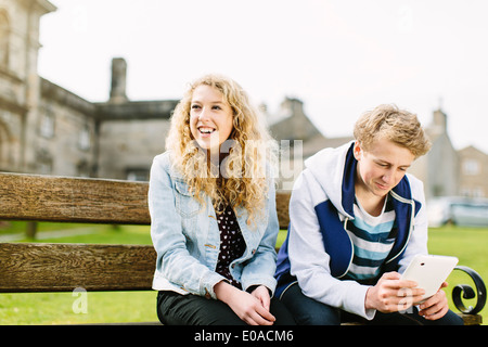 Teenager Bruder und Schwester auf Bank sitzend Stockfoto