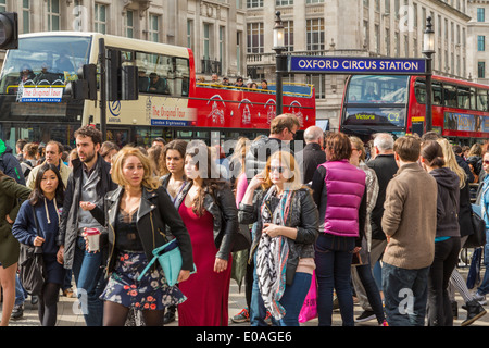 Geschäftige Touristen und Pendler, die an einem geschäftigen Tag an der Oxford Circus U-Bahn-Station in Londons bester Einkaufsstraße Oxford Street, England, vorbeilaufen Stockfoto