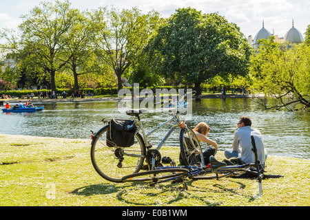 Junge Menschen entspannen neben dem See an einem sonnigen Tag im Regents Park London UK Stockfoto