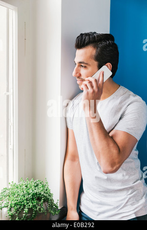 Porträt des jungen Mannes telefonieren mit Smartphone in seiner Küche Stockfoto