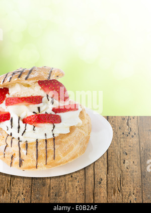 Windbeutel mit Erdbeeren und Schlagsahne auf Holz, Sommer Stockfoto