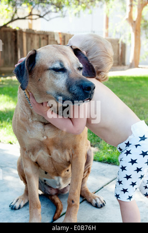 Weiblichen Kleinkind umarmt Alter Hund Stockfoto