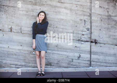 Junge Frau stehend, Wand gelehnt Stockfoto