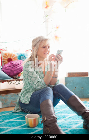 Reife Frau sitzen auf Stock SMS auf Handy Stockfoto