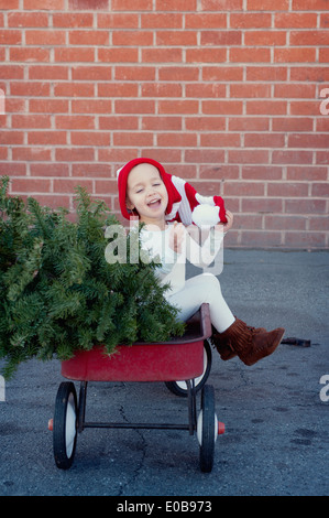 Mädchen sitzen im Trailer mit Weihnachtsbaum Stockfoto