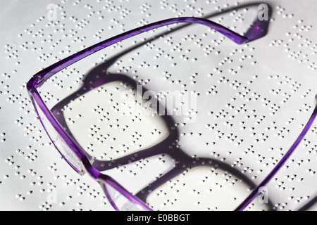 Gläser und ein Buch in Blindenschrift. Lesung mit Hindernis, Eine Brille Und Ein Buch in Blindenschrift. Lesen Mit Behinderung. Stockfoto