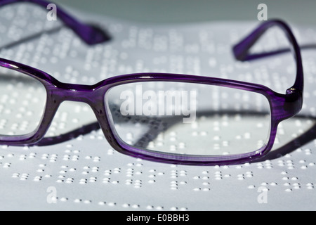 Gläser und ein Buch in Blindenschrift. Lesung mit Hindernis, Eine Brille Und Ein Buch in Blindenschrift. Lesen Mit Behinderung. Stockfoto