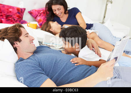 Familie entspannend im Bett mit Kaffee und Zeitung Stockfoto
