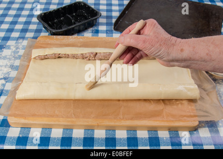 Herstellung von Wurst Brötchen mit fertig gerollten Teig Hand Bürsten mit Ei (11 von 58) Stockfoto