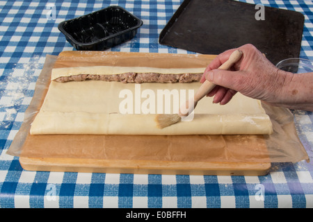 Machen Wurst Brötchen mit fertig gerollten Teig und Würstchen Würstchen in Ort und hand Bürsten mit Ei (12 von 58) Stockfoto