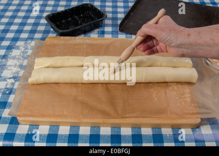 Machen Wurst Brötchen mit fertig gerollten Teig und Würstchen gerollt und Hand Bürsten mit Ei (13 von 58) Stockfoto