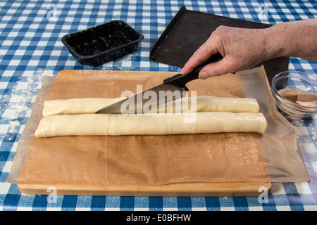 Machen Wurst Brötchen mit fertig gerollten Gebäck und Wurst Hand mit Messer um zu schneiden Sie die Brötchen (16 von 58) Stockfoto