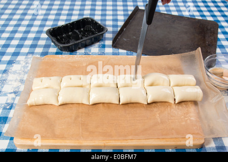 Wurstbrötchen mit bereit gerollten Teig mit Würstchen Rollen machen aus und schneiden Sie die Löcher / Muster auf der Oberseite (21 von 58) Stockfoto