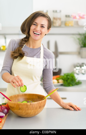 Glückliche junge Frau machen Salat in Küche Stockfoto
