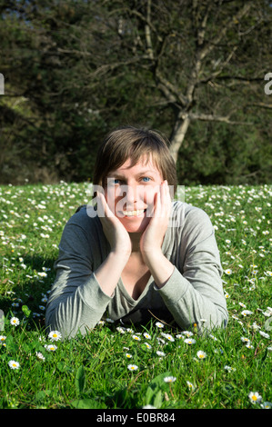 Schöne junge Frau liegt auf dem Gänseblümchen Blumen Feld. Stockfoto