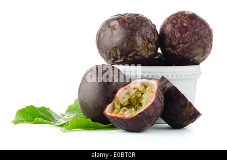 Frische Passionsfrucht mit grünen Blättern und weißen Keramikschale isoliert auf weißem Hintergrund Stockfoto