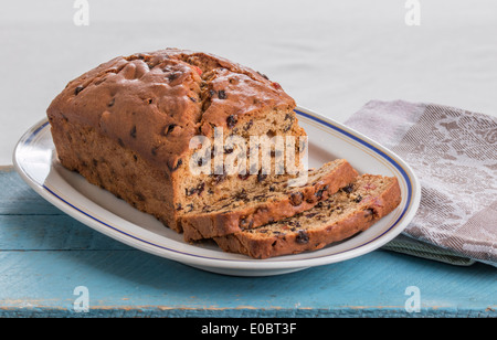 Obst Brot /cake mit Scheiben auf einem weißen Teller mit einem blauen Rand auf einem blauen Brett und eine Küche/Geschirrtuch (18 19) Stockfoto