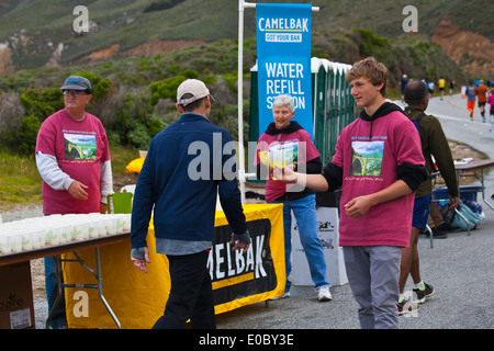 Läufer sind Erfrischungen gesponsert von Camelback auf dem Highway 1 während der 2014 Big Sur Marathon - BIG SUR, Kalifornien angeboten. Stockfoto