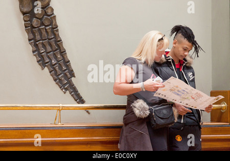 Junges Paar am Natural History Museum London UK, mit dinosaurierknochen aus dem Fin eines versteinerten Pleiosaur. Stockfoto