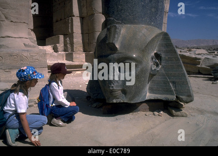 Zwei kleine Mädchen von Angesicht zu Angesicht mit dem Kopf von Ramses II, Ramesseum, Luxor, Ägypten Stockfoto