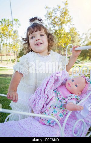 Entzückende junge Baby Mädchen spielt mit ihren Babydoll und Beförderung im Freien. Stockfoto