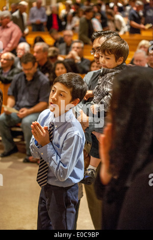 Ein gut gekleideter junger Hispanic Gemeindemitglied St. Timothy katholische Kirche, Laguna Niguel, CA, wartet in der Schlange für die Gemeinschaft zum Abschluss der Messe. Hinweis jüngerer Bruder auf der rechten Seite. Stockfoto