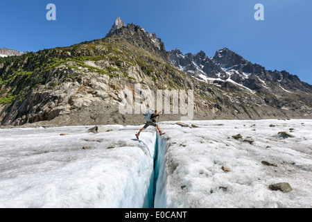 Springen über Gletscherspalte am Gletscher Mer de Glace, Chamonix, Alpen, Frankreich, EU Stockfoto