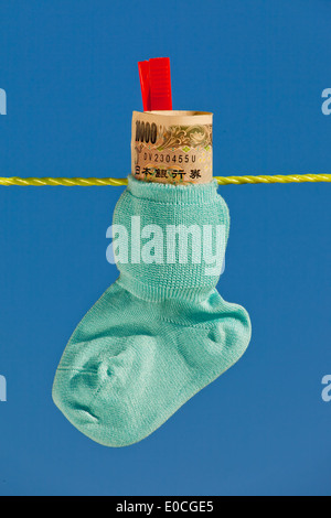 Baby Socken auf der Wäscheleine mit Yen Banknoten aus Japan., Baby Socken Auf Waescheleine Mit Yen Geldscheinen aus Japan. Stockfoto