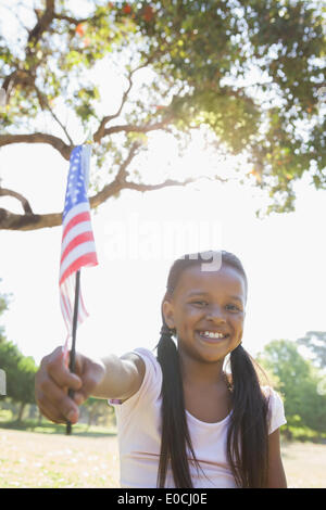 Kleines Mädchen sitzen auf dem Rasen, die amerikanische Flagge winken Stockfoto