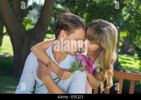 Süßes Paar umarmt im Park mit Mädchen mit Blumen Stockfoto