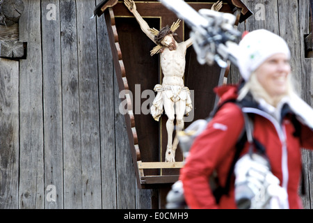 Junge Skifahrerin, vorbei an einem Wegkreuz sehen, Tirol, Österreich Stockfoto