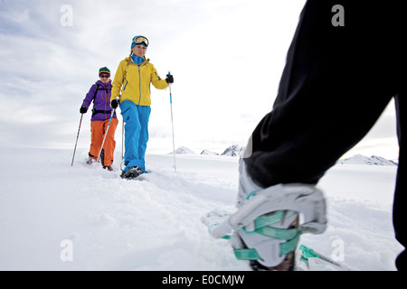 Drei junge Frauen, die auf den Berg in ihren Schneeschuhen wandern sehen, Tirol, Österreich Stockfoto