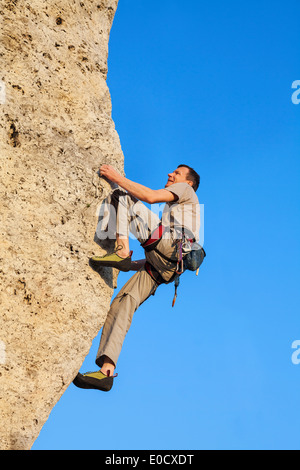 Extreme Klettern, Mann auf natürliche Mauer mit blauem Himmel. Stockfoto