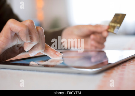 Reife Frauen-digital-Tablette Closeup Hände Plastikkarte Shop im Haus Stockfoto