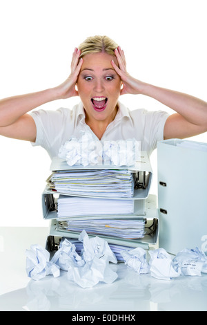 Eine junge Frau verzweifelt im Büro zwischen vielen Dateien und zerknüllte Papier. Symbolische Foto für Stress, Burnout und Nacharbeiten. Stockfoto