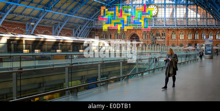 Eine junge Frau prüft ihre Eurostar-Tickets mit David Batchelors Chromolocomotion im Hintergrund St. Pancras Station London UK Stockfoto