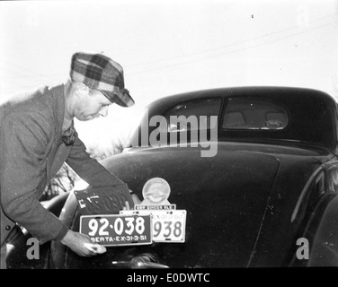 Unbekannter Mann seine Automobile Kfz-Kennzeichen ändern Stockfoto