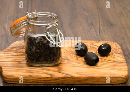 Oliven und Olivenpaste auf einem Holzbrett Stockfoto