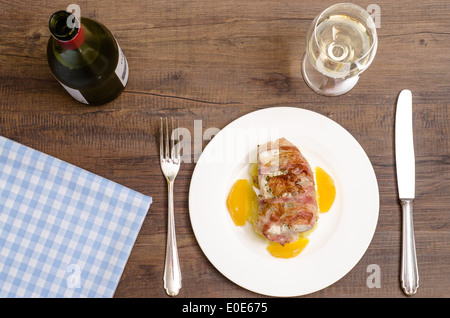 Roastad Fisch mit Speck und Weißwein auf einem braunen Holztisch Stockfoto