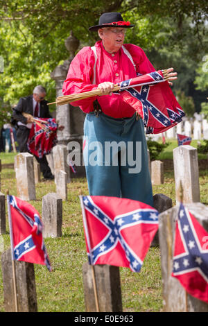 Ein Bürgerkrieg Re-Enactor sammelt Flaggen von Grabstätten, die nach einer Feier Confederate Memorial Day auf Magnolia Cemetery 10. April 2014 in Charleston, SC. Confederate Memorial Day ehrt die rund 258.000 verbündeten Soldaten, die im amerikanischen Bürgerkrieg gestorben. Stockfoto