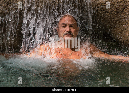 Mann genießt eine erfrischende Wassermassage im Mayfield Falls, Glenbrook, Jamaika Stockfoto