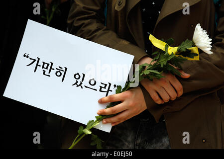 Seoul, Südkorea. 10. Mai 2014. Ein Teilnehmer hat ein Zeichen und eine Blume während "Still bleiben" Schweigemarsch gegen das, was sie darauf bestehen, lax Reaktion des President Park Geun-hyes Regierung nach der Fähre eingesunken war Sewol aus der südwestlichen Insel Jindo am 16. April 2014, auf der Straße, Seoul, Südkorea, am Samstag, 10. Mai 2014 Gewässer. Zeichen zu lesen, "Stillhalten", Kapitän der Sewol pasquinading, wurde, die eine Nachricht für die Fahrgäste bis auf weiteres warten, wenn die Fähre, nach den örtlichen Medien sank Rundfunk. Stockfoto