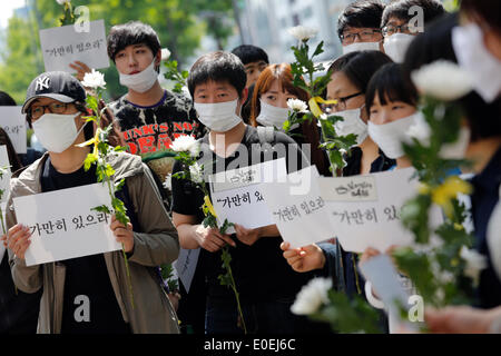 Seoul, Südkorea. 10. Mai 2014. Menschen halten Schilder und Blumen während ihrer "bleiben immer noch" stillen Marsch gegen das, was sie darauf bestehen, lax Reaktion des President Park Geun-hyes Regierung nach der Fähre eingesunken war Sewol aus der südwestlichen Insel Jindo am 16. April 2014, auf der Straße, Seoul, Südkorea, am Samstag, 10. Mai 2014 Gewässer. Zeichen zu lesen, "Stillhalten", Kapitän der Sewol pasquinading, wurde, die eine Nachricht für die Fahrgäste bis auf weiteres warten, wenn die Fähre, nach den örtlichen Medien sank Rundfunk. Stockfoto