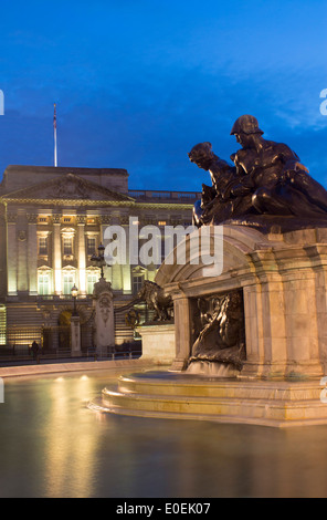 Buckingham-Palast in der Nacht mit Victoria Memorial Statuen spiegelt sich im Wasser des Brunnens London England UK Stockfoto